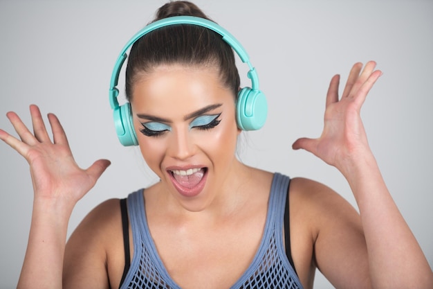 Schließen Sie herauf Porträt des erstaunten tanzenden Mädchens, das Musik mit den Kopfhörern lokalisiert über Studiohintergrund hört Aufgeregtes junges Mädchen mit Kopfhörern Drahtlose Kopfhörer