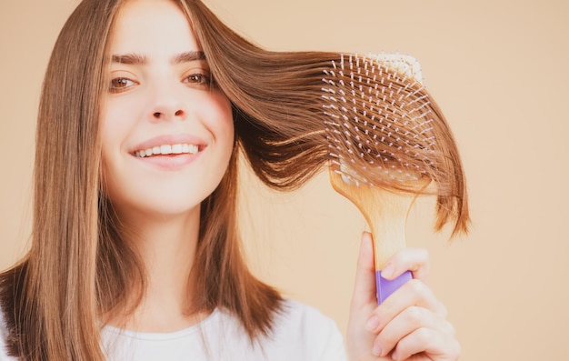 Schließen Sie herauf Porträt des glücklichen schönen Mädchens mit dem glänzenden Haar mit Kamm Attraktive lächelnde Frau brushin