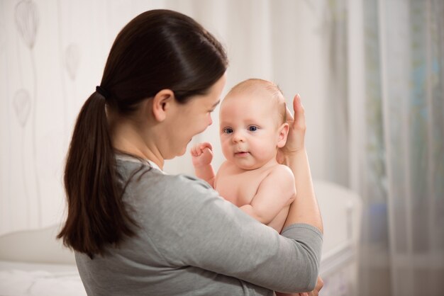 Schließen Sie herauf Porträt des schönen jungen Muttermädchens, das ihr neugeborenes Baby küsst.