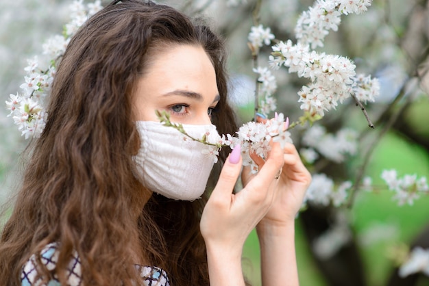 Foto schließen sie herauf porträt des zarten weibchens unter einem blühenden baum mit einer maske