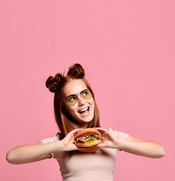 Schließen Sie herauf Porträt einer hungrigen jungen Frau, die den Burger lokalisiert über weißem Hintergrund isst