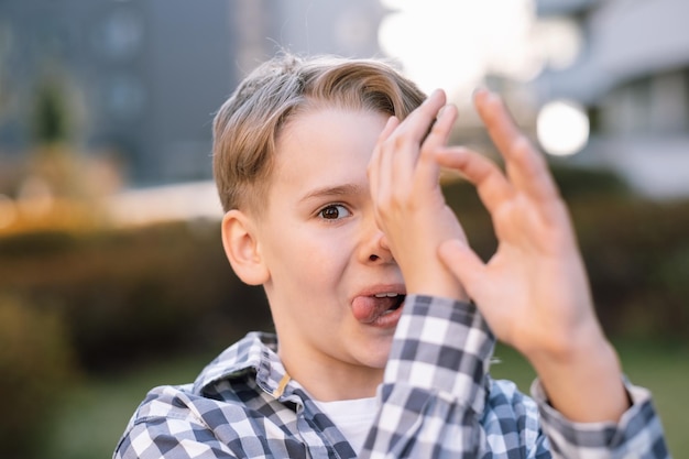 Schließen Sie herauf Porträt eines jungen frechen Teenagermannes mit einem schelmischen Ausdruck Skurriler junger Mann draußen