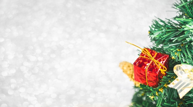 Schließen Sie herauf rote Geschenkbox auf grünem Weihnachtsbaum am weißen bokeh Lichthintergrund