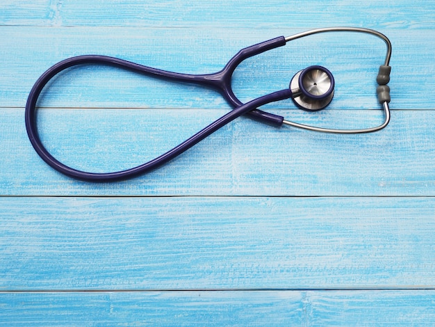 Schließen Sie herauf Stethoskop auf blauem hölzernem Hintergrund mit Kopienraum. Gesundheitswesen und medizinisches Konzept. Ansicht von oben.