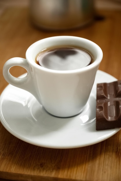 Schließen Sie herauf Tasse Espressokaffee mit Stück Schokolade auf Platte