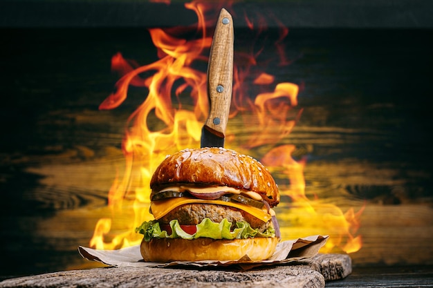 Schließen Sie leckeren Rindfleischburger auf einem Holztisch mit einem Messer hinein