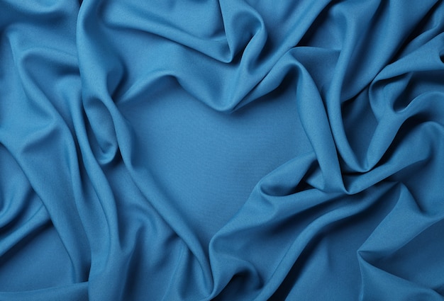Schließen Sie oben abstrakten textilen Hintergrund der herzförmigen blauen gefalteten Falten des Gewebes