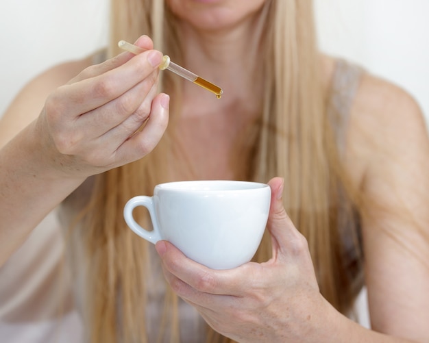 Schließen Sie oben auf der blonden Frau des mittleren Alters, die eine Tasse hält