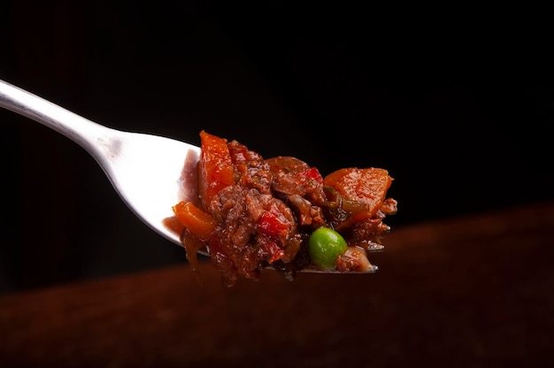 Schließen Sie oben auf der Gabel, die Portion Fleisch mit Karotten und Erbsen Makro serviert