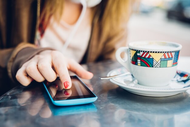 Schließen Sie oben auf der Hand der jungen Frau den Bildschirm eines intelligenten Telefons klopfend