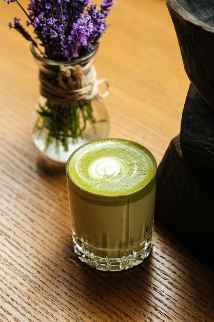 Schließen Sie oben auf grünem Matcha-Getränk in einem Glas auf dem Holztisch