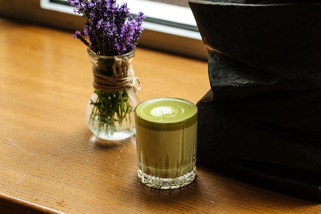 Schließen Sie oben auf grünem Matcha-Getränk in einem Glas auf dem Holztisch
