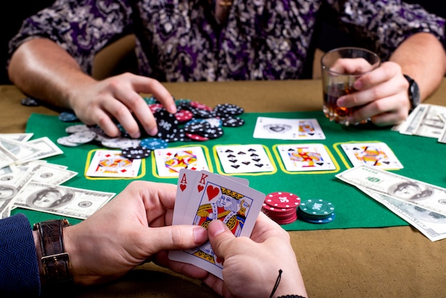 Schließen Sie oben auf Karten in den Händen des Mannes am Pokertisch