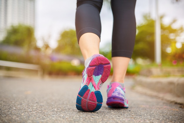 Schließen Sie oben auf Schuh, die Läuferathletenfüße, die morgens auf Straße unter Sonnenlicht laufen.