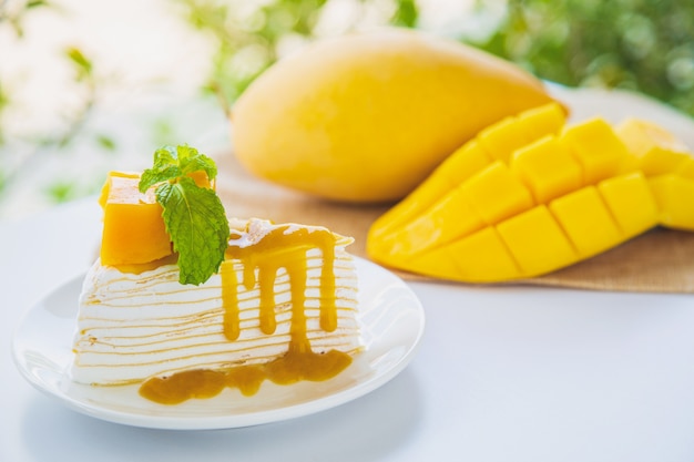 Schließen Sie oben Mango Crêpe Kuchen geschnitten auf einem weißen Teller dekoriert