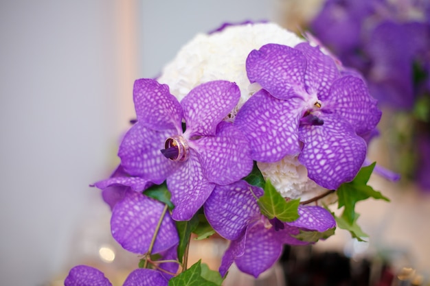 Schließen Sie oben vom purpurroten Orchideenhochzeitsblumenstrauß mit Ringen