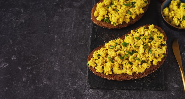 Schließen Sie oben von den bunten veganen Eiersalat-Sandwiches auf schwarzem Hintergrund