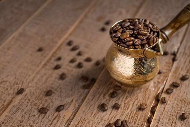 Schließen Sie oben von den frischen Röstkaffeebohnen in Cezve auf Holztisch.