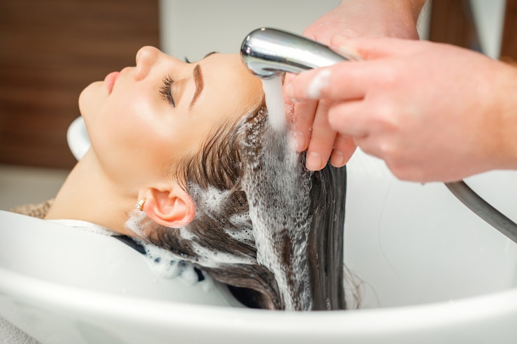 Foto schließen sie oben von den händen des friseurs, der haar der frau im waschbecken am schönheitssalon wäscht