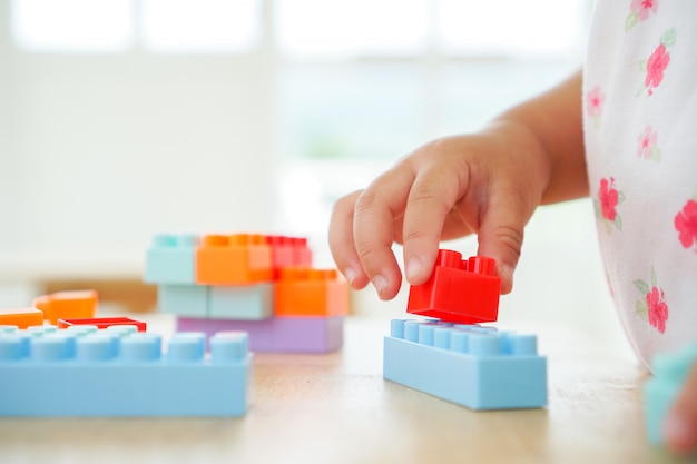 Schließen Sie oben von den Händen des Kindes, die mit bunten Verbindungsstückspielwaren am Tisch spielen. Lernspielzeug für Vorschul- und Kindergartenkinder.