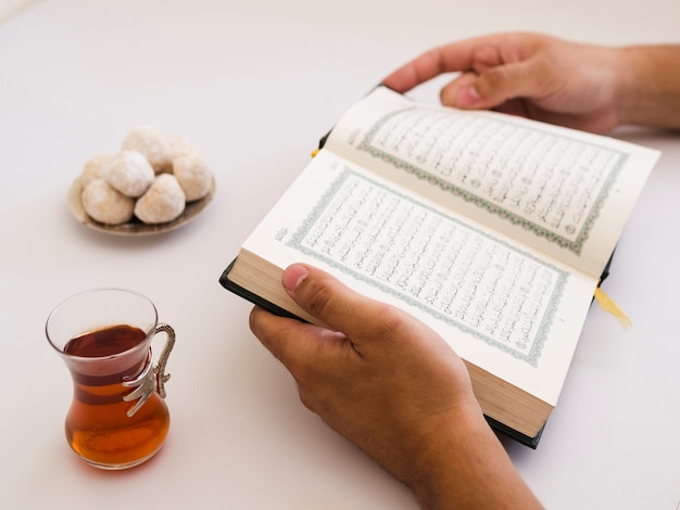 Foto schließen sie oben von den händen, die quran auf tabelle halten