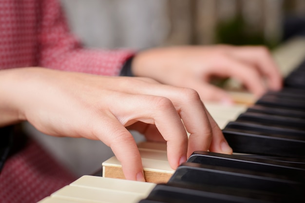 Schließen Sie oben von den Händen eines kleinen begabten Mädchens, das zu Hause Klavier spielt