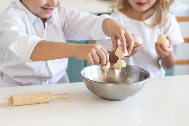 Schließen Sie oben von den Kinderhänden, die mit Eiern kochen