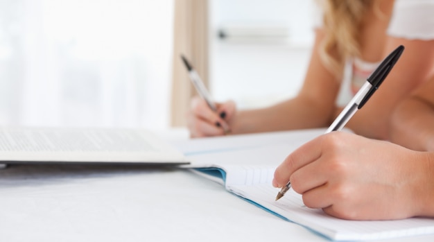 Schließen Sie oben von den Studenten, die an einem Tisch sitzen, der ihre Hausarbeit tut