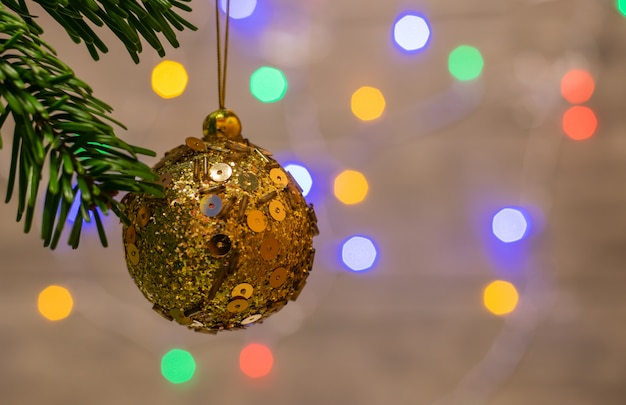 Schließen Sie oben von den Verzierungen auf einem Zweig Weihnachtsbaum und von Hintergrund mit bunten Lichtern