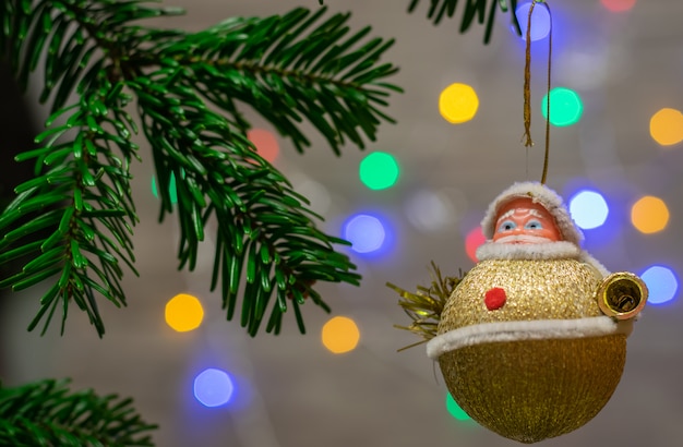 Schließen Sie oben von den Verzierungen auf einem Zweig Weihnachtsbaum und von Hintergrund mit bunten Lichtern