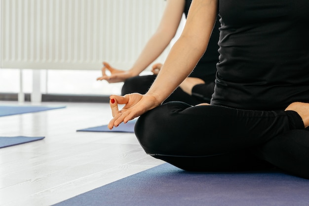 Schließen Sie oben von den Yoga-Frauen, die im Lotus asana während des Yoga-Kurses sitzen, beschnittene Ansicht