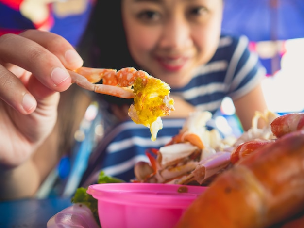 Schließen Sie oben von der Asiatin, die lokale gegrillte Meeresfrüchte von Thailand-Strand isst.