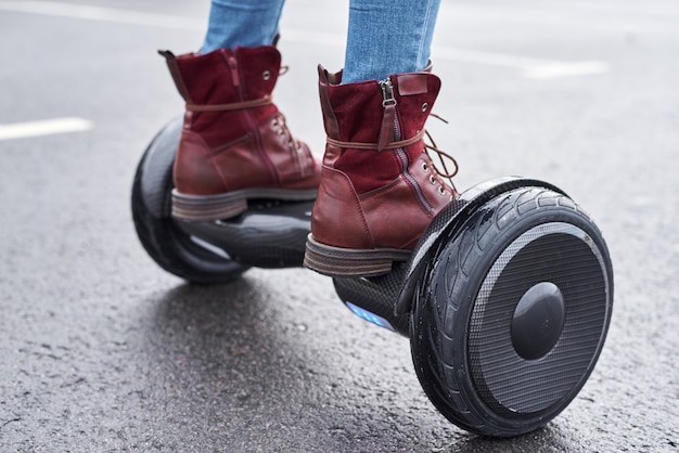 Schließen Sie oben von der Frau, die Hoverboard auf Asphaltstraße verwendet. Füße auf Elektroroller im Freien