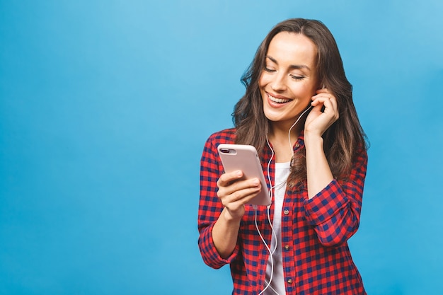 Schließen Sie oben von der glücklichen jungen Dame, die unter Verwendung der Telefonhörmusik in den Kopfhörern steht