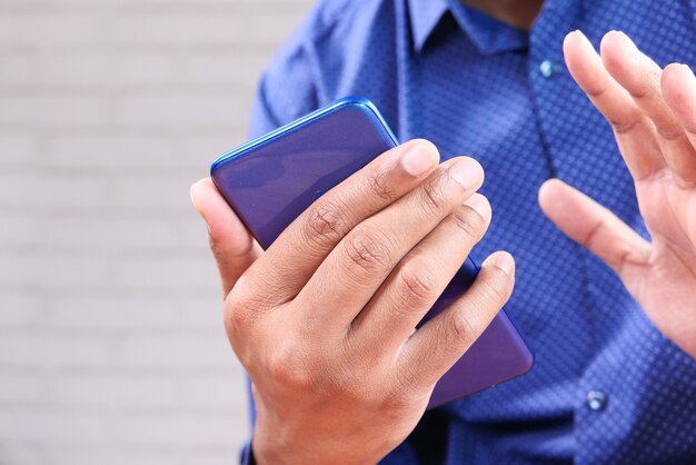Schließen Sie oben von der Hand des jungen Mannes unter Verwendung des Smartphones