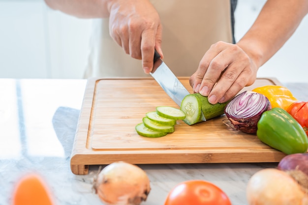 Schließen Sie oben von der Mannhand, die Gemüse in der Küche für das Vorbereiten des Abendessens kocht und schneidet