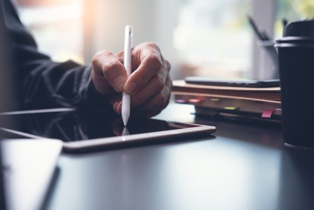 Schließen Sie oben von der Mannhand unter Verwendung des Touchscreen-Stifts auf digitalem Tablett auf Bürotisch