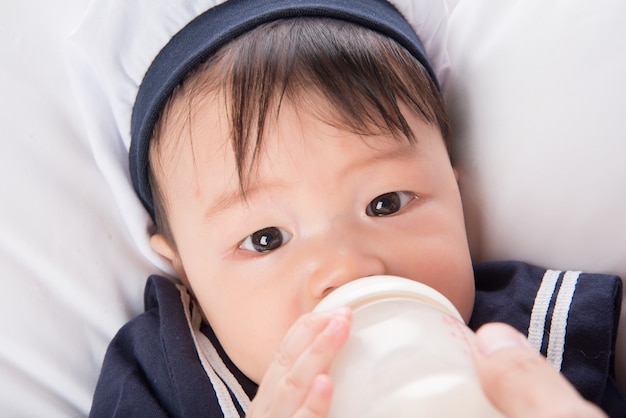 Schließen Sie oben von der trinkenden Mutter des asiatischen Babykindes, die von der Flasche stillt