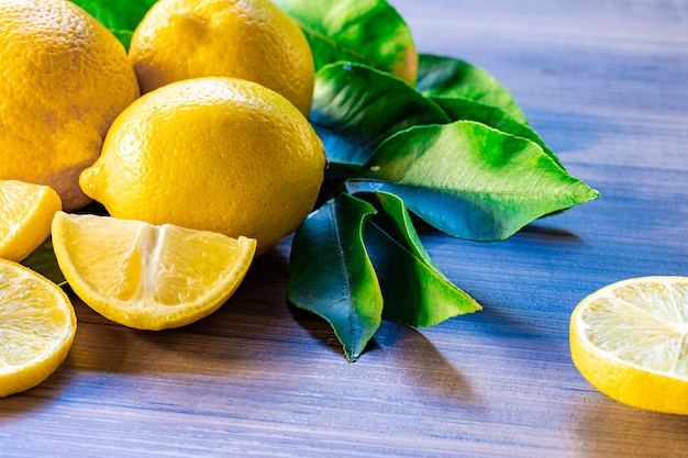 Schließen Sie oben von der Zitrone und den grünen Blättern auf rustikalem Holztisch
