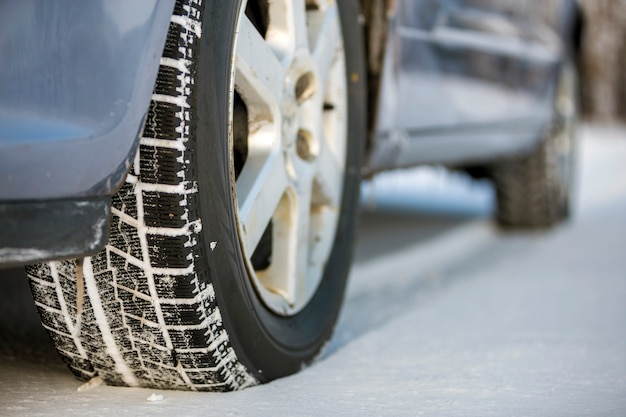 Schließen Sie oben von einem Autoreifen, der auf schneebedeckter Straße am Wintertag geparkt wird. Transport- und Sicherheitskonzept.