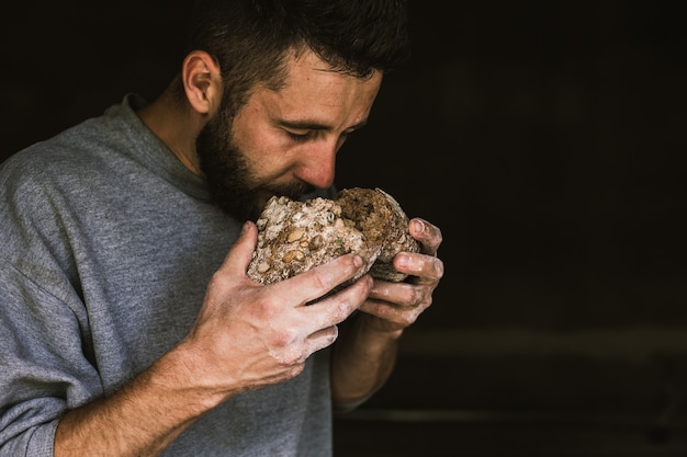 Schließen Sie oben von einem jungen bärtigen Mann, der köstliches frisch gebackenes Brot riecht