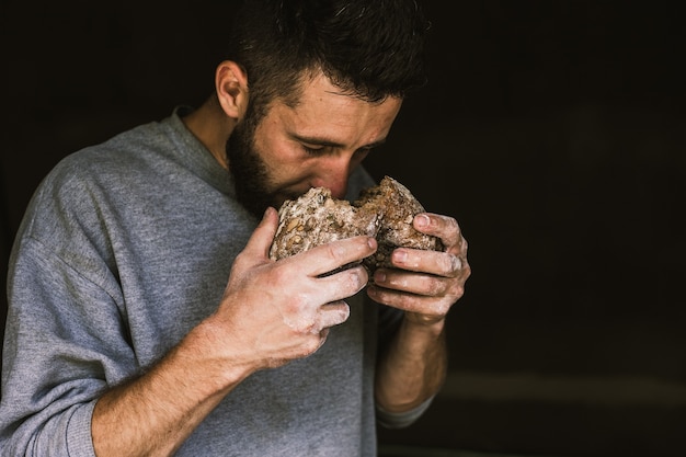 Schließen Sie oben von einem jungen bärtigen Mann, der köstliches frisch gebackenes Brot riecht