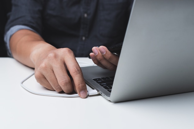 Foto schließen sie oben von einem mann, der ein mobiltelefon mit einem laptop auflädt