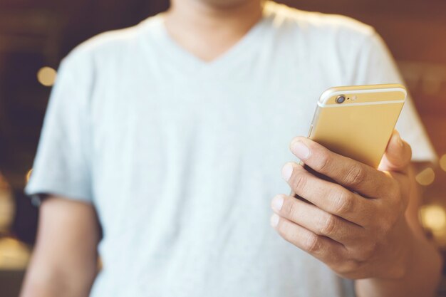 Schließen Sie oben von einer Mannhand, die unter Verwendung des mobilen Smartphone-Außenhandys im öffentlichen Park hält.