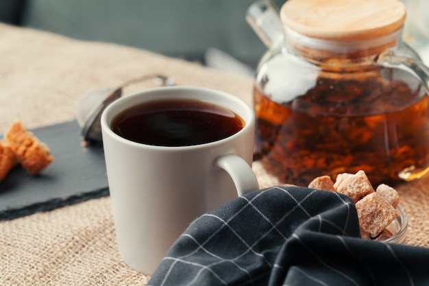 Schließen Sie oben von einer Tasse Tee und von den Süßigkeiten auf Holztisch