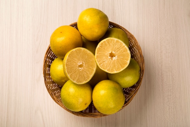 Schließen Sie oben von einigen Orangen in einem Korb über einer Holzoberfläche. Frisches Obst.