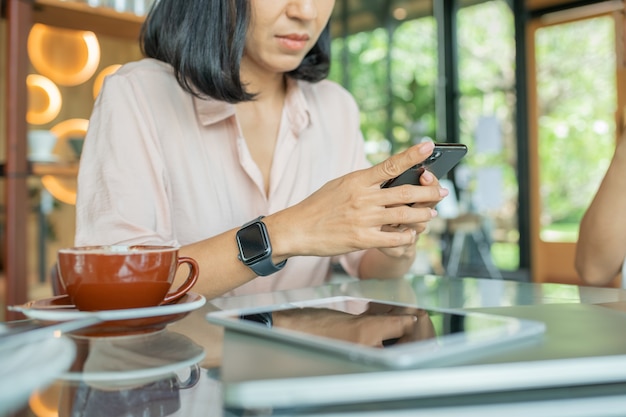 Schließen Sie oben von Frauenhänden, die Handy mit leerem Kopierplatzbildschirm für Ihre Werbetextnachricht oder Werbeinhalt halten, weibliche Lesung Nachrichten auf Handy während Ruhe im Café