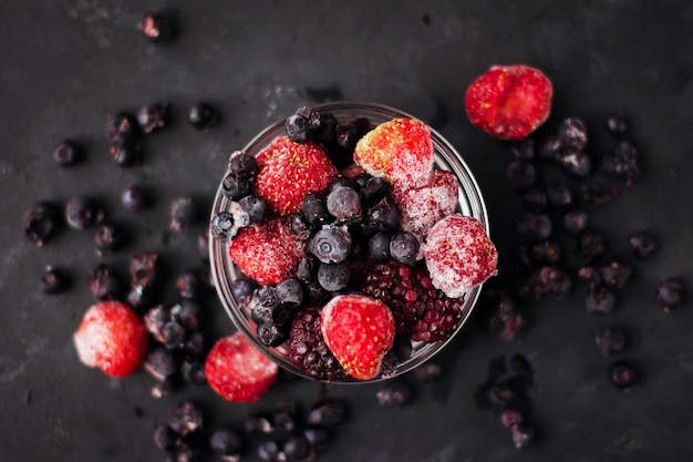 Schließen Sie oben von gefrorenen gemischten Früchten und Beeren auf einem schwarzen Tisch Gesundes Essen Vitamine Snack Dessert