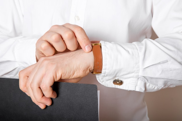 Foto schließen sie oben von geschäftsmann, der uhr auf seiner hand freien raum betrachtet. mann im weißen hemd, das zeit von luxusarmbanduhren prüft. bräutigam hochzeitsvorbereitung.