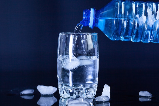 Schließen Sie oben von Glaswasser mit Eis und Plastikflasche